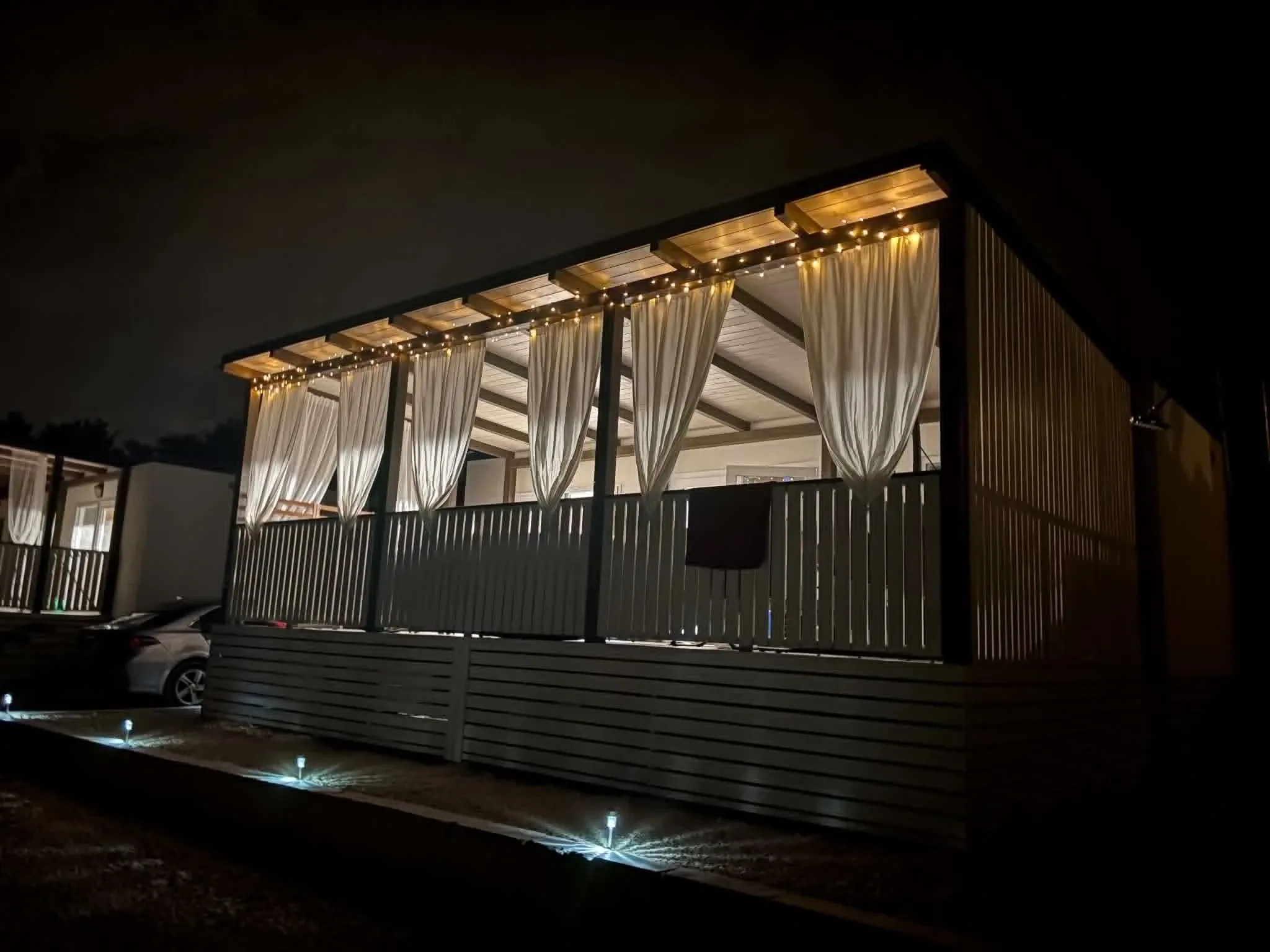 The house lit up at night with string lights, sheer curtains and solar path lights