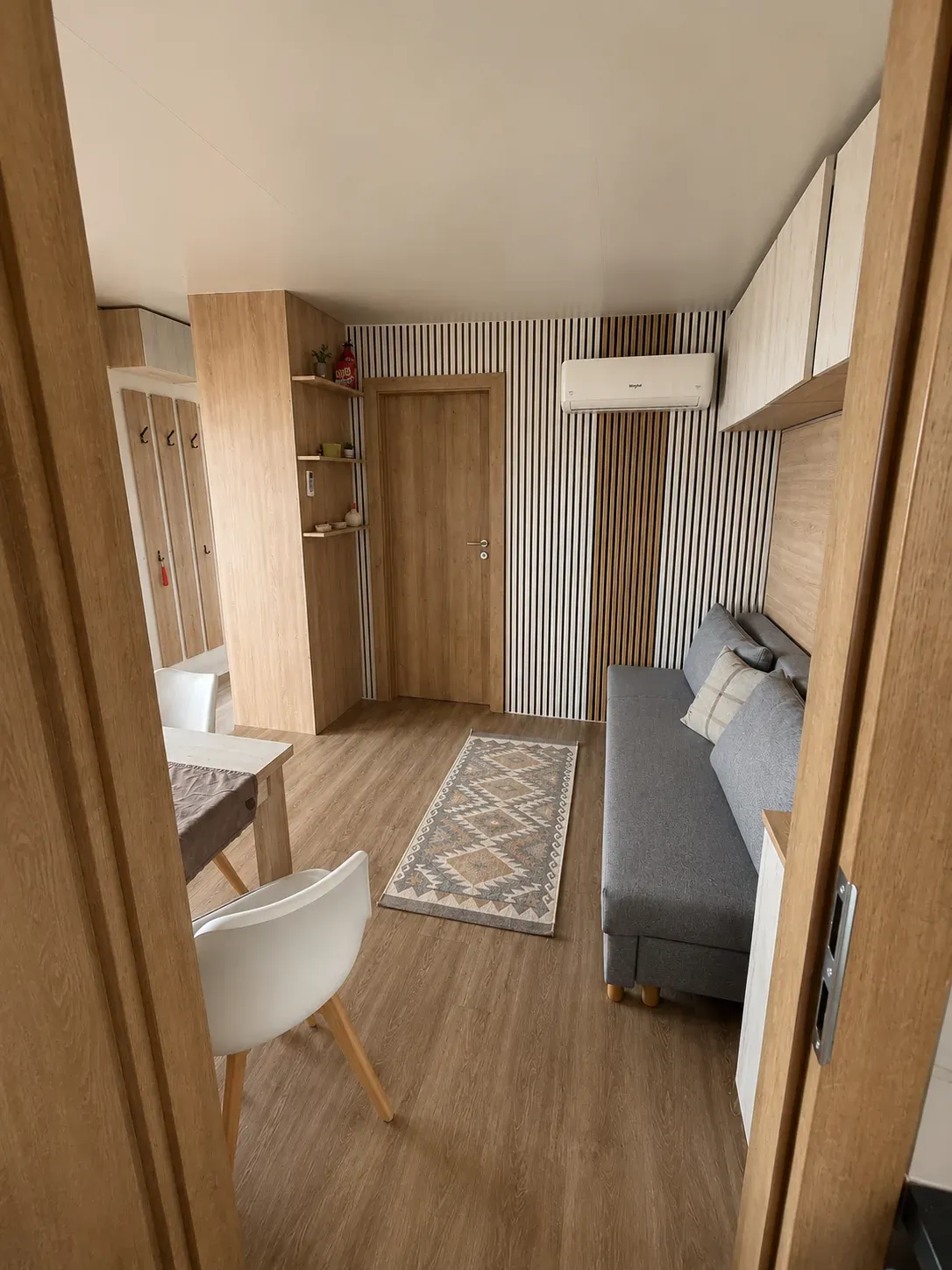 Living room with sofa bed, dining nook and coat rack