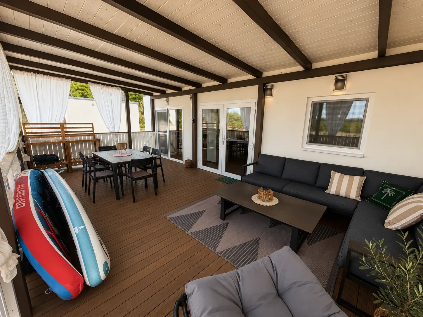 Terrace with dining table, lounge sofa and SUP boards by the railing