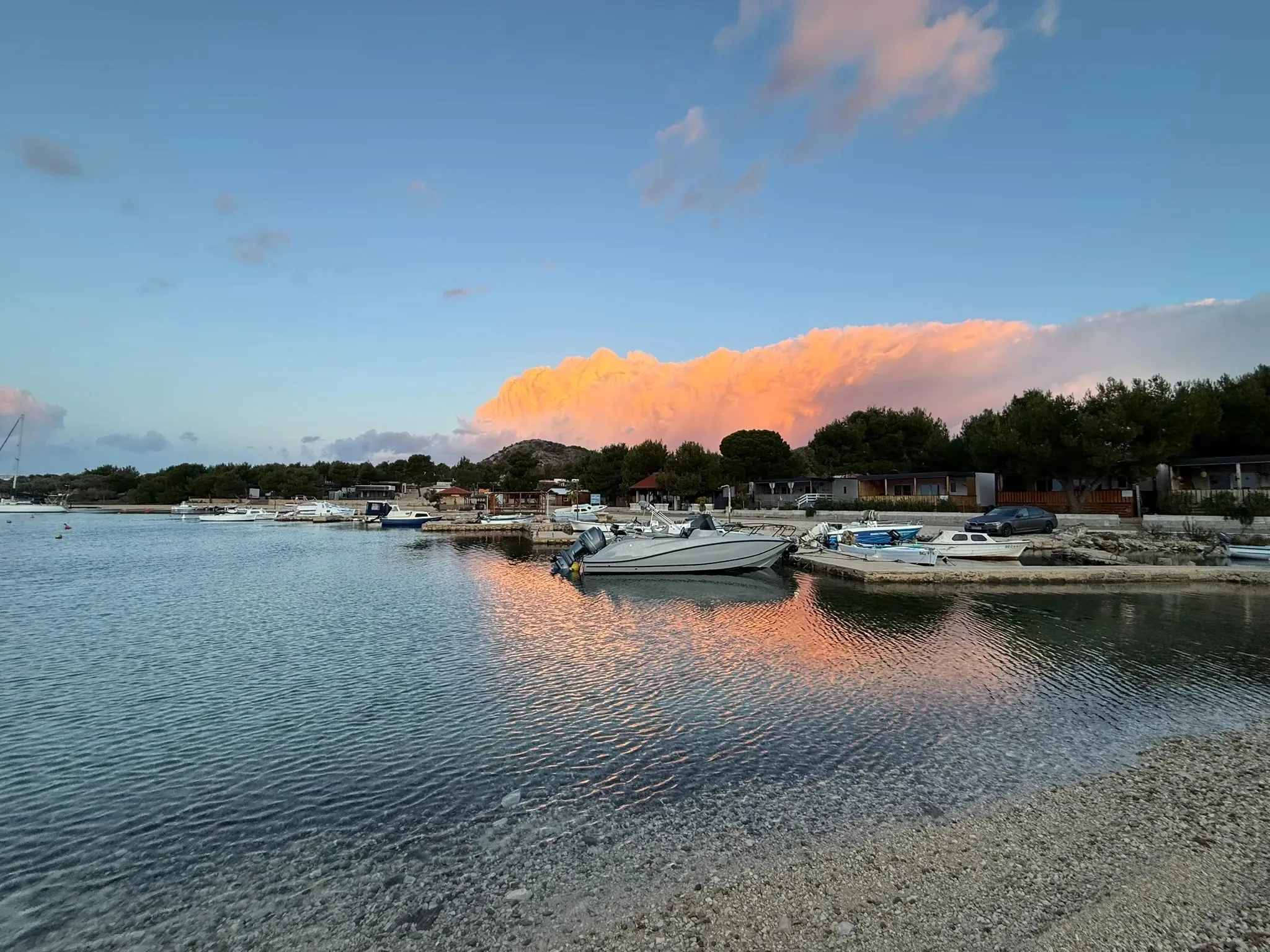 Small harbor in Drage at sunset with boats, calm water and pink clouds